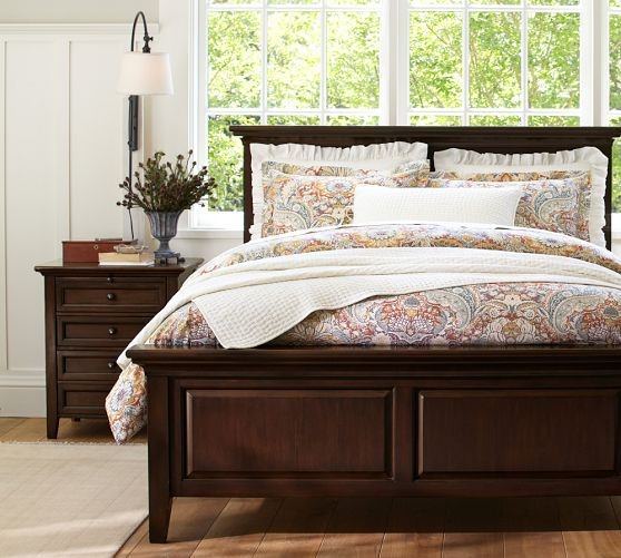 اتاق خواب مستر با تخت چوبی قهوه ای و پارکت کرم که روی تخت آن روتختی طرح دار زیبا پهن شده است